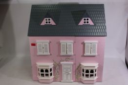 A pink-coloured wooden doll's house. Dolls house is 60 1/2 cm (l) x 45 cm (w) x 62 cm (h).