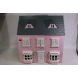 A pink-coloured wooden doll's house. Dolls house is 60 1/2 cm (l) x 45 cm (w) x 62 cm (h).