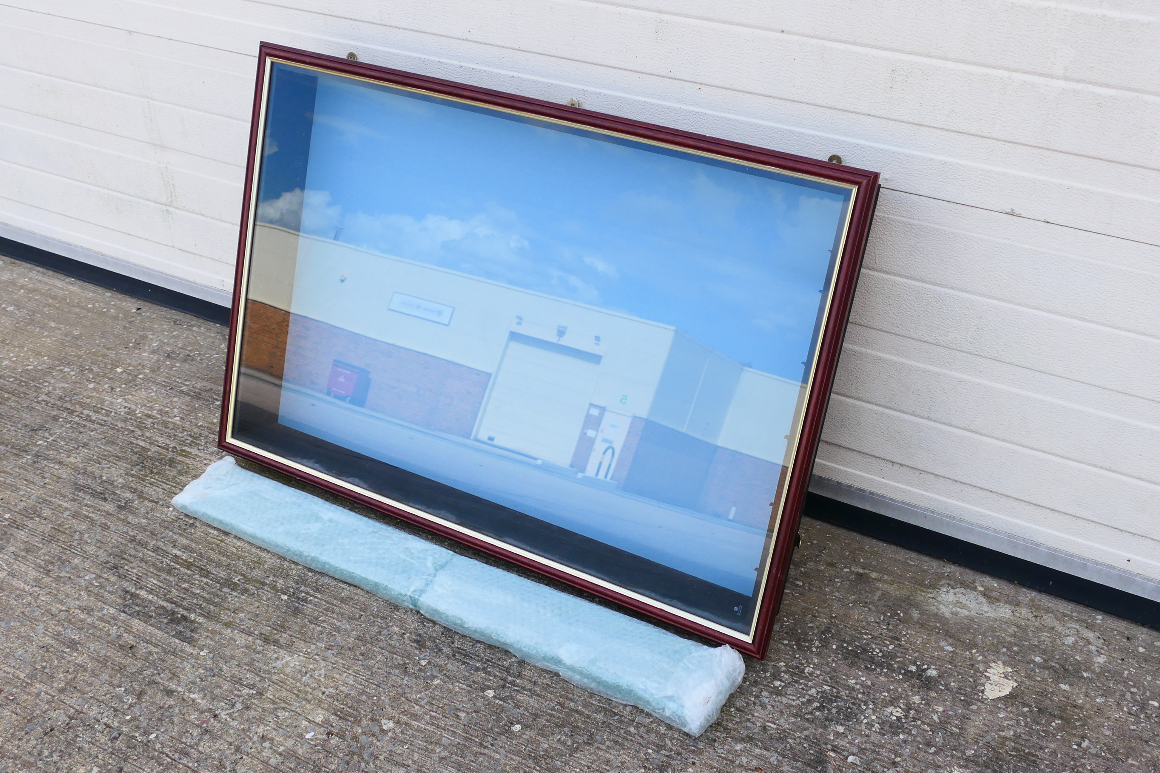 A large wall mounted glass fronted dark wood display cabinet with glass shelves (horizontal