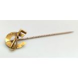 A Victorian 15 carat yellow gold lapel pin in the shape of a horseshoe and ridding crop.