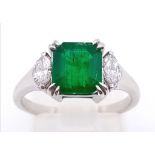 An 18K White Gold, Emerald and Diamond Ring. Emerald-cut centre stone with a marquise cut diamond