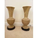 A Pair of Large Beige Polished Stone Vases. Both on dark wooden stands. 56cm tall. 20cm width.