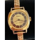 Vintage TRAFALGAR WRISTWATCH finished in gold tone and having square face with black and gold dial.