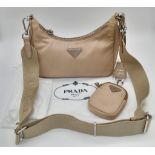 A Prada Mini-Hobo Bag in Desert Beige Nylon. Comes with a detachable pouch on an adjustable strap.