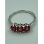 9 ct WHITE GOLD and RUBY RING having a three stone RUBY trilogy mounted to top. Full UK Hallmark.