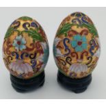 Two very ornamental Chinese cloisonné eggs on wooden base. Height: 7 cm