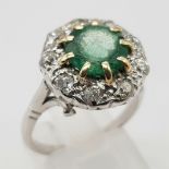 An 18K White Gold (tested) Emerald and Diamond Ring. Central round cut emerald surrounded by a