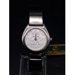 A ladies COIN WATCH in original presentation box. 25 mm case, stainless steel construction, in new/