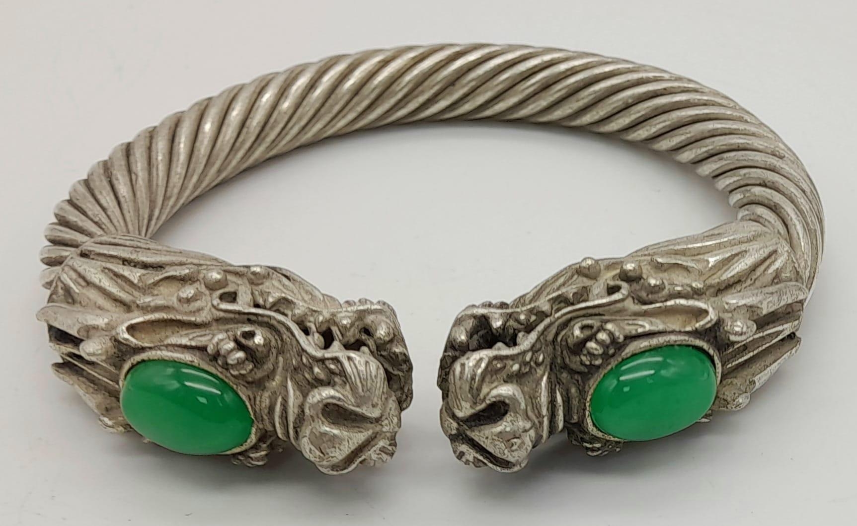 A Tibetan Silver Twin Dragon Twisted Bangle/Bracelet with Green Jade head decoration. 7cm inner