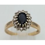 A 9K Yellow Gold Sapphire and Diamond Ring. Oval sapphire with diamond halo and further diamonds