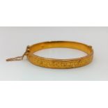 A Vintage 9K Yellow Gold Bangle. Clip opening with safety chain. Scrolled decoration. 6cm inner