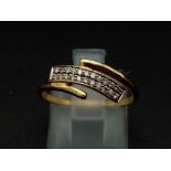 An 18K yellow gold ring with two diamond cross over bands. (diamonds 0.10 carats). Ring size: M1/