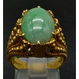 An 18k yellow gold natural jadeite cabochon ring with beaded ornate decoration. Size M. 11g total