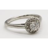 An 18K White Gold and Diamond Ring. 0.25ct brilliant round cut central diamond (approx) surrounded