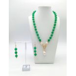 A multi-faceted green jade necklace and earrings set, adorned with large, natural, white, baroque
