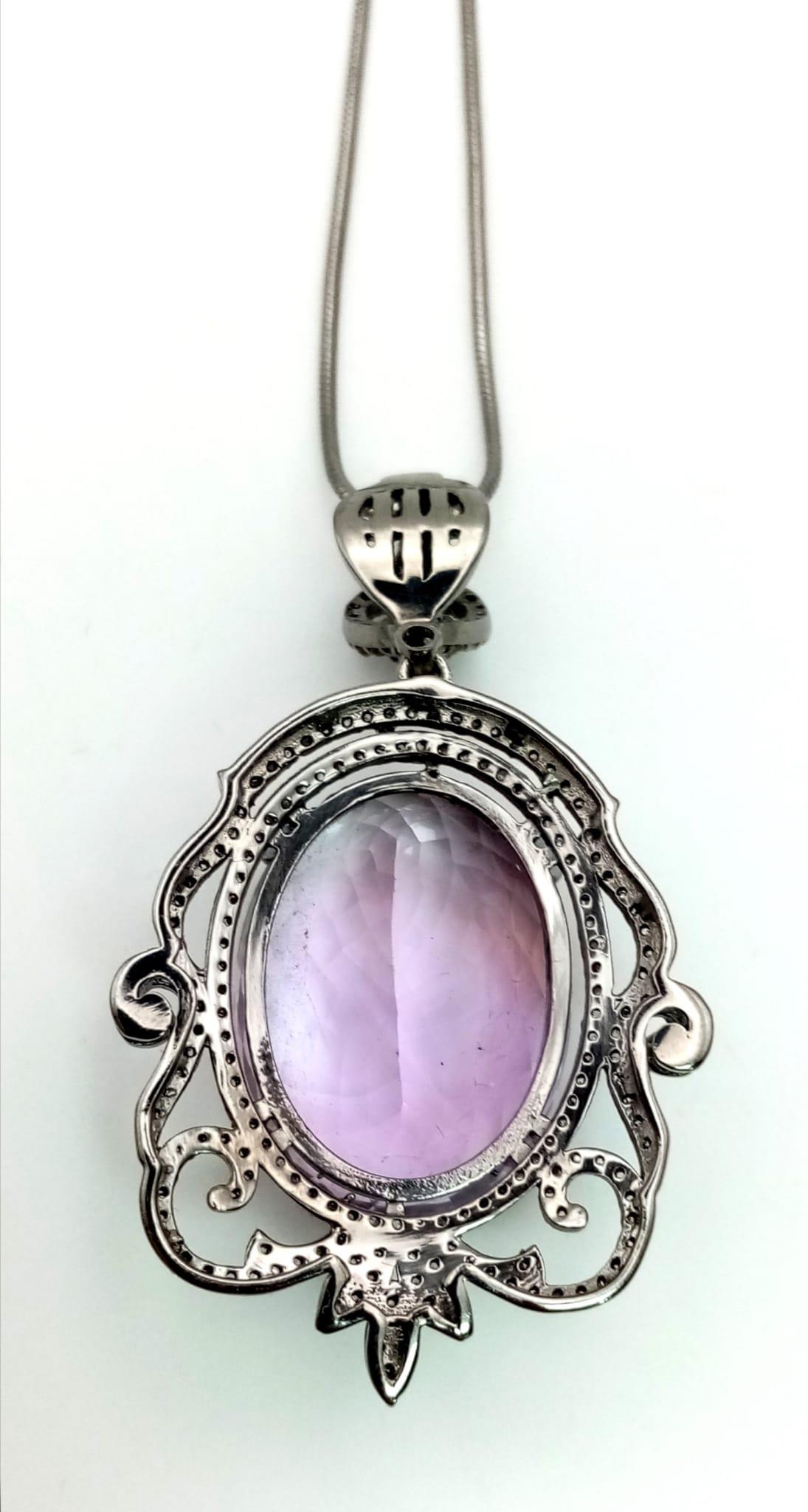 A 42.75ct Natural Oval cut Amethyst Pendant, set in 925 silver, decorated with a Diamond surround. - Image 2 of 4