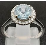 A 14k White Gold Aquamarine and Diamond Ring. Central round-cut aquamarine with a diamond surround