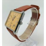 A Vintage Favre-Leuba Daymatic Watch. Brown leather strap. Square case - 30mm. Peach dial with