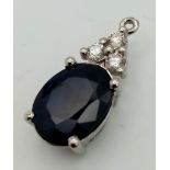 An 18K white gold pendant with an oval cut sapphire and three round cut diamonds. Height: 18 mm,