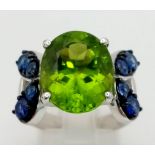 A very attractive, platinum ring with a large, oval cut peridot, surrounded by eight, round cut