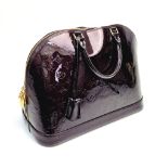 A Louis Vuitton Amarante Alma Vernis Handbag. Patent purple monogram leather. Gilded zip and