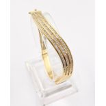 An Elegant 14K Yellow Gold and Diamond Wave Bracelet. Over 100 bright round-cut diamonds. (3ct