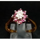 An 18K Yellow Gold Ruby and Diamond Ring. Central small diamond with a ruby gemstone halo. Size M