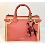 A Burberry Red Leather Handbag. Two tone exterior with teddy bear mascot. Gold-tone hardware.