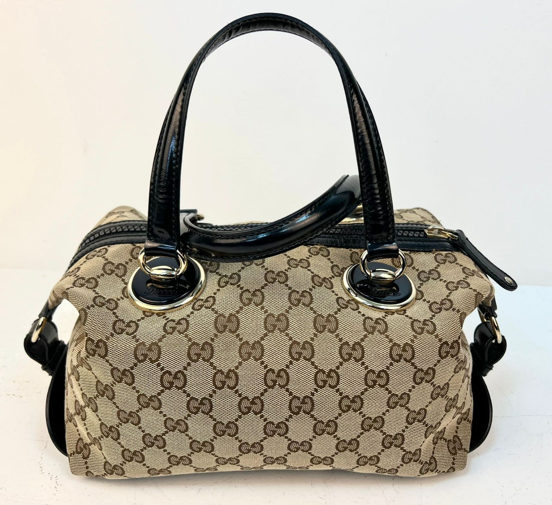 A Gucci Abbey Handbag. Monogram beige cotton exterior with black leather trim. Gucci logo black disc