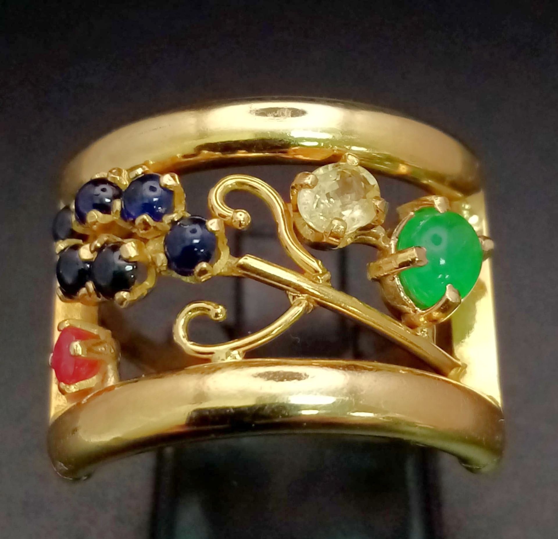An 18 K yellow gold ring with an artistic design and adorned with an emerald cabochon, plus ruby,