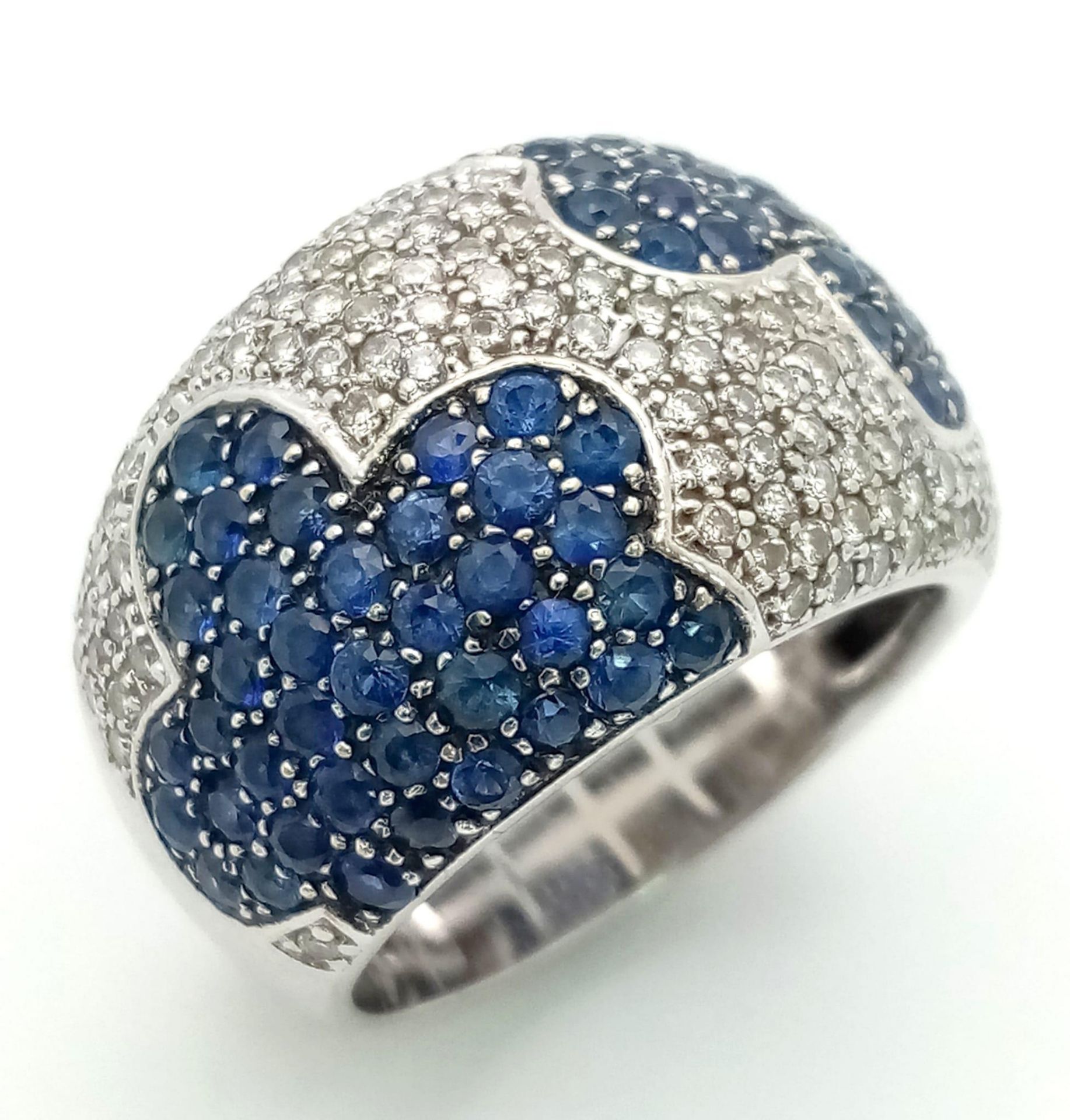 An 18K White Gold Sapphire ad Diamond Cluster Ring. Mirror image sapphire clouds in a diamond sky.