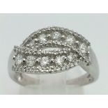 An 18K White Gold and Diamond Cluster Crossover Ring. 0.60ct approx. Size O. 4.8g total weight.