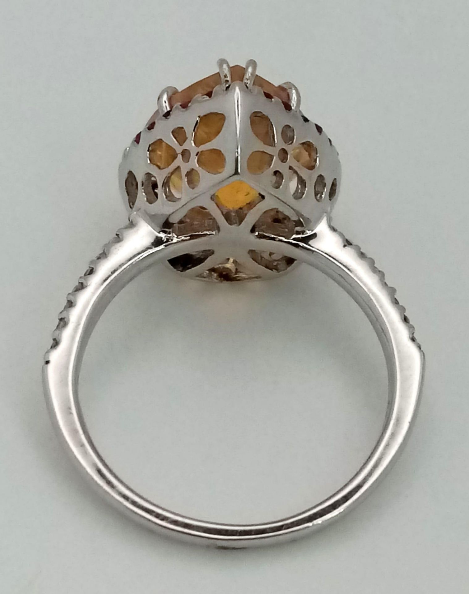 An 18K white gold ring with a pear cut fire opal surrounded by rubies and diamonds on the - Image 3 of 4