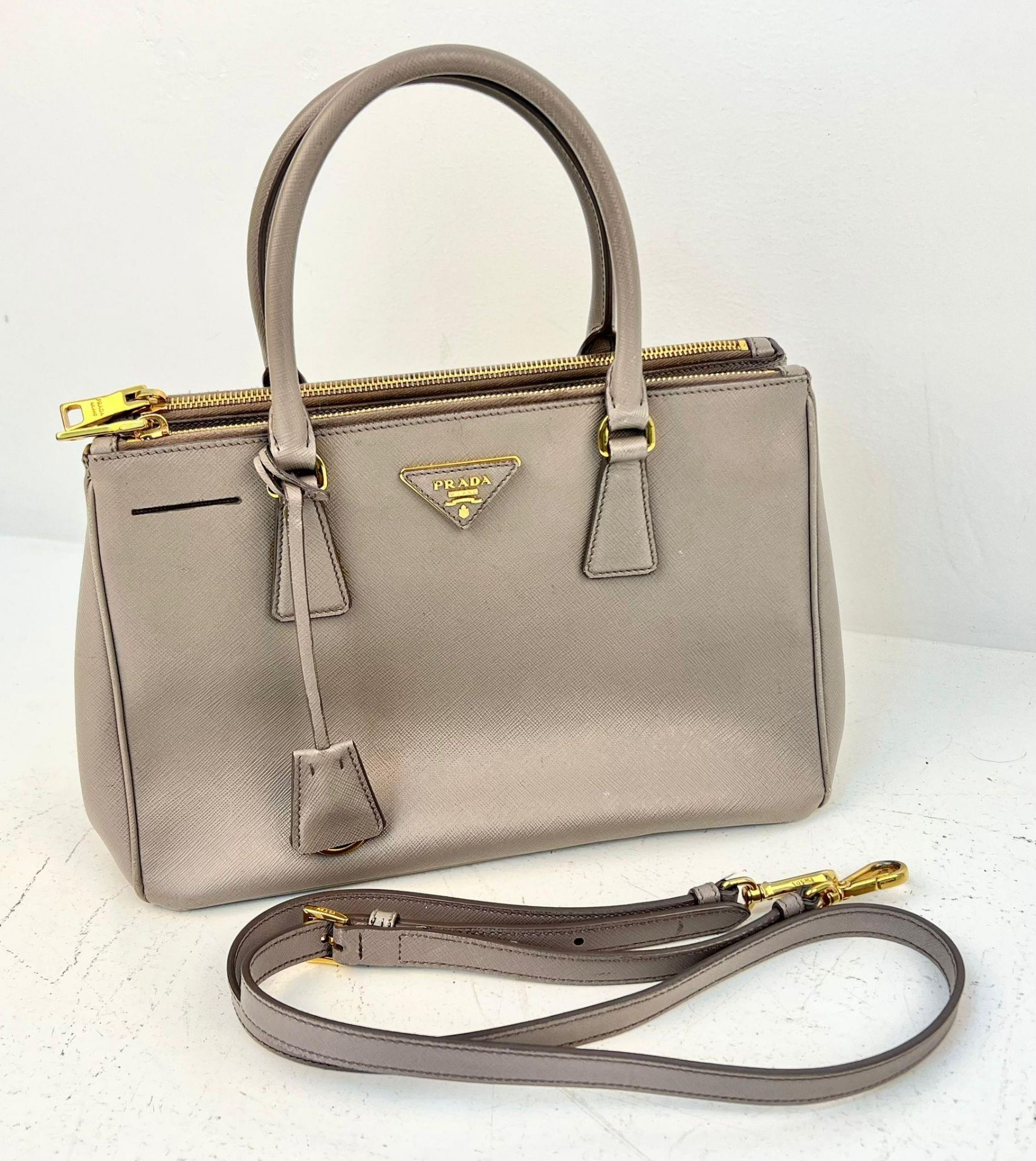 A Prada Saffiano Galleria Handbag with Shoulder Strap. Luxurious grey leather exterior. Three