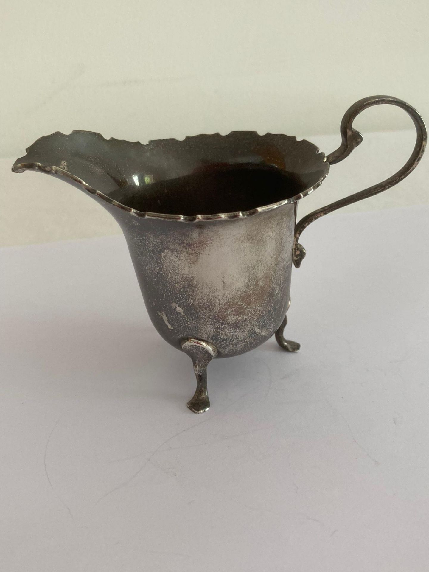 Antique SILVER CREAM JUG standing on three paw-foot legs with scroll handle. Clear hallmark for Adie