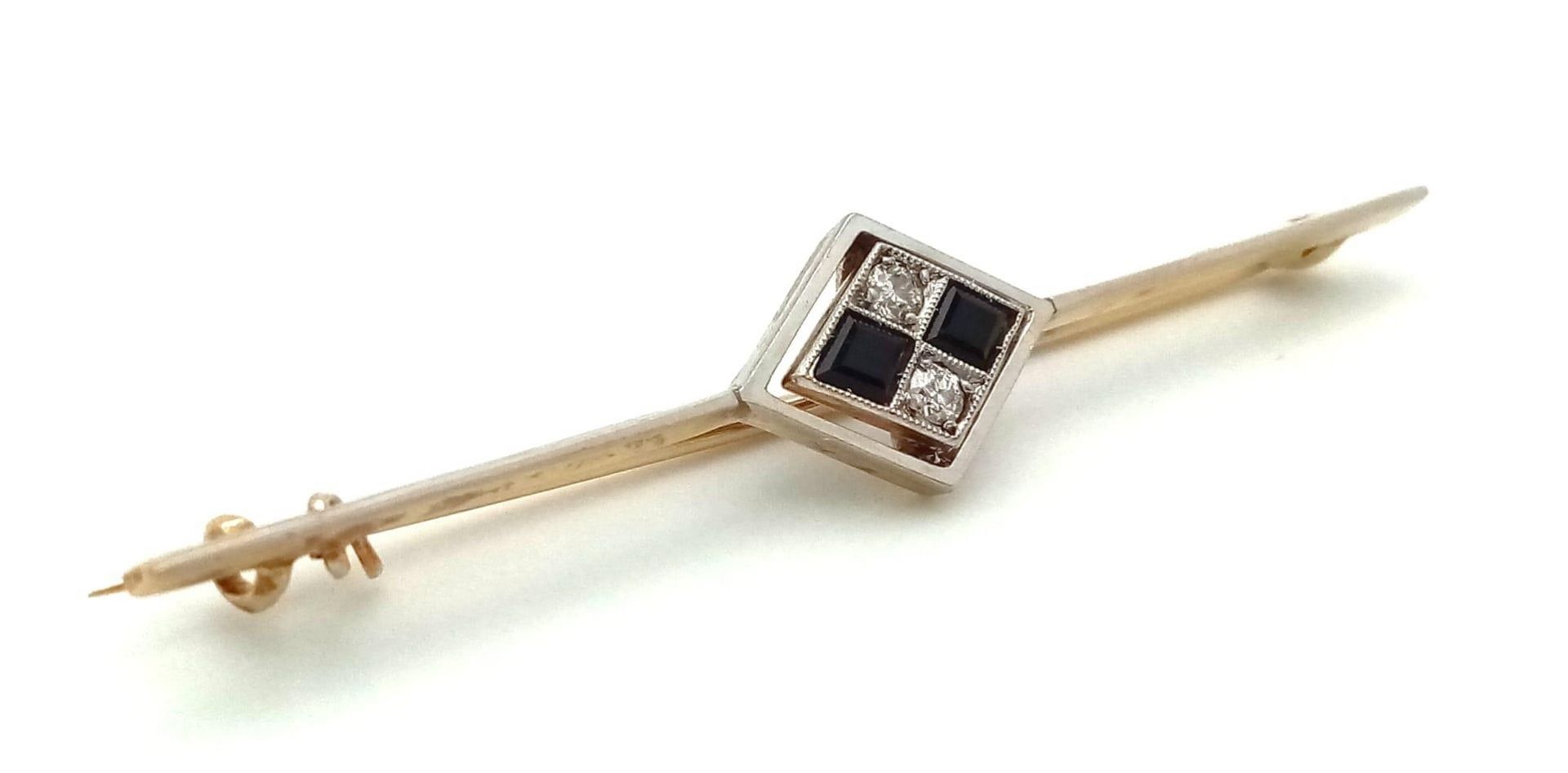 An Art Deco Diamond and Onyx Brooch in 18K Gold and Platinum. 5.5cm. 3.75g total weight.