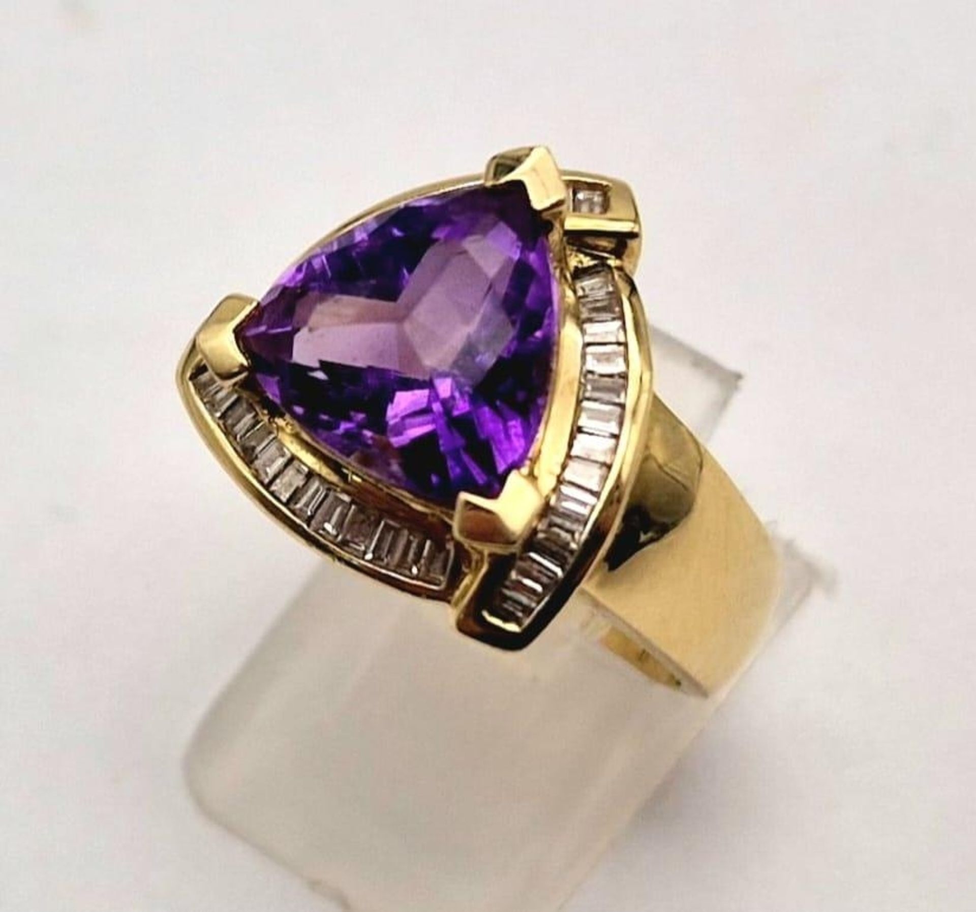 A 14K GOLD RING WITH LARGE TRIANGULAR AMETHYST CENTRE STONE SURROUNDED BY DIAMONDS. 11.9gms size P