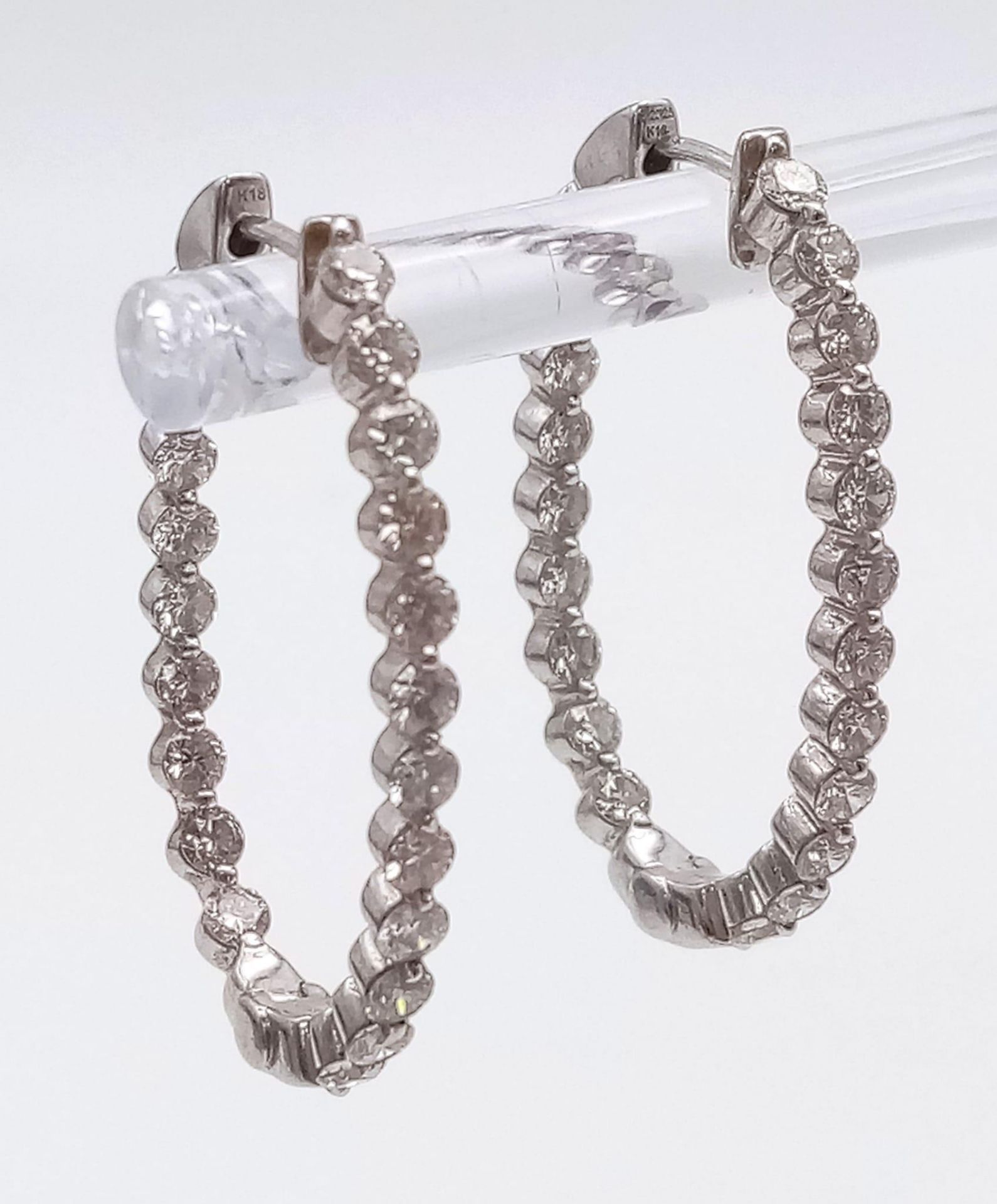 A PAIR OF 18K WHITE GOLD AND DIAMOND EARRINGS IN A HORSE SHOE HOOP SHAPE . 6.6gms 21 small