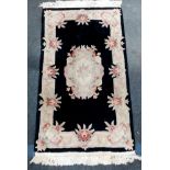A VINTAGE HEAVY QUALITY CHINESE FRINGED RUG IN BLACK CLASSIC PATTERN . 150 X 92cms a/f