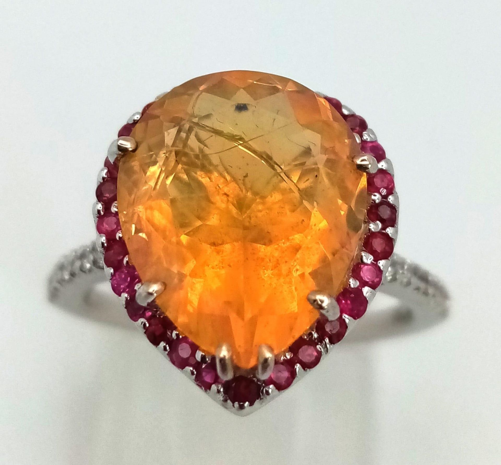 An 18K white gold ring with a pear cut fire opal surrounded by rubies and diamonds on the - Image 2 of 4