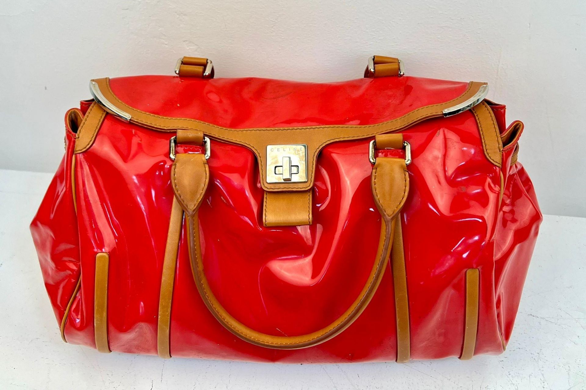 A Celine Red Patent Tote Bag. Brown leather handles and trim. Spacious interior with zipped