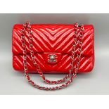 A Chanel Patent Leather Flap Handbag. Bright red patent leather quilted exterior. Classic Chanel