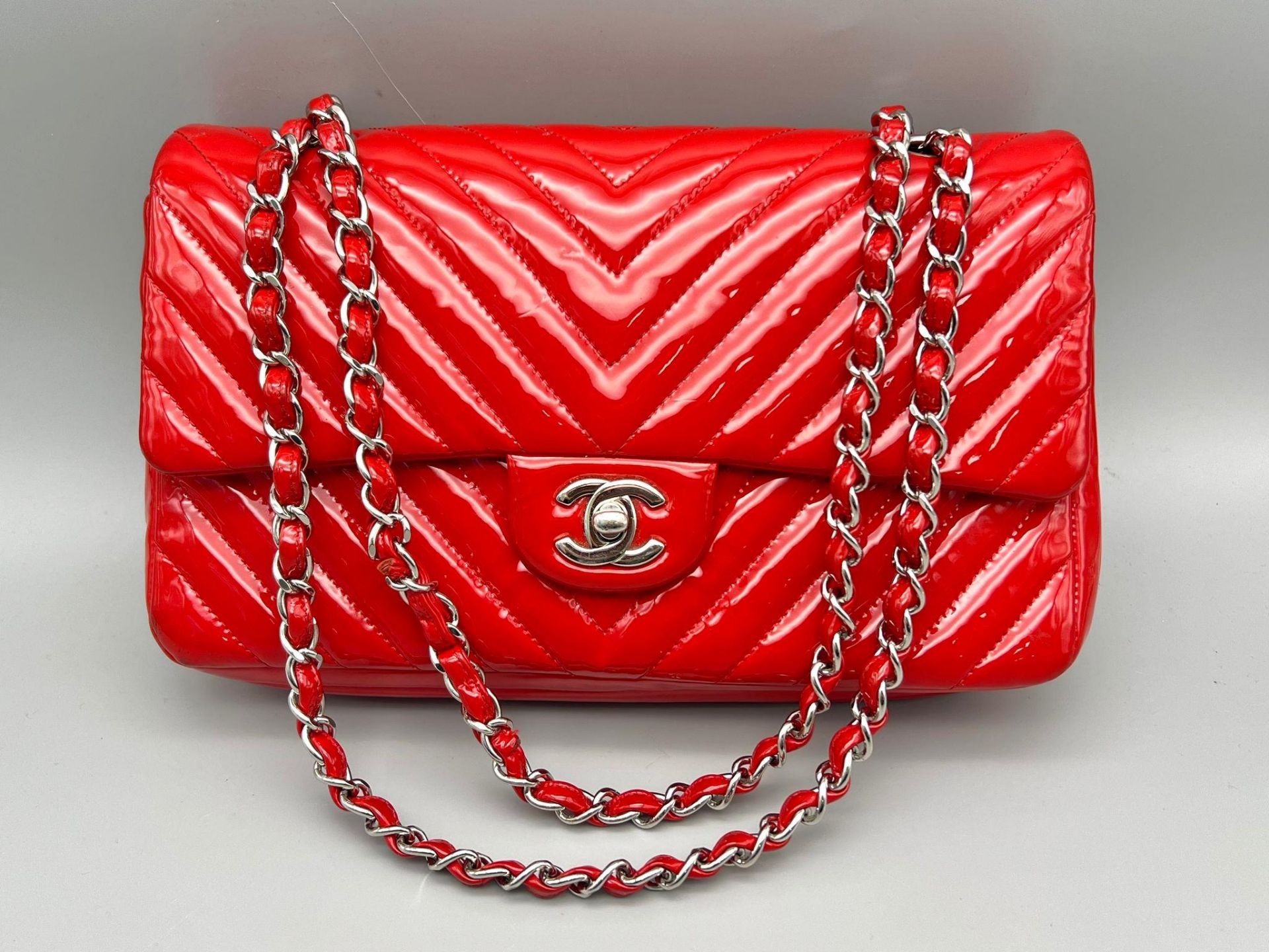 A Chanel Patent Leather Flap Handbag. Bright red patent leather quilted exterior. Classic Chanel