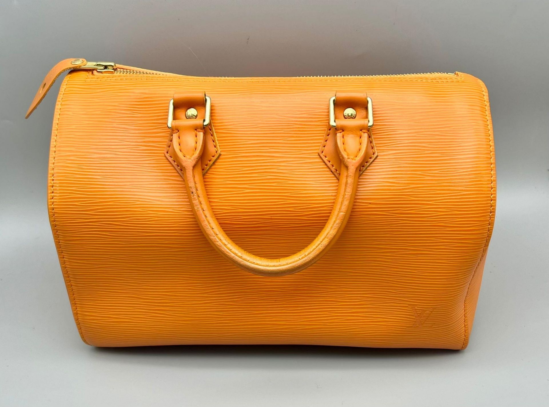 A Louis Vuitton Mandarin Epi Leather Speedy Bag. Twin handles with a zipped top. Orange textile