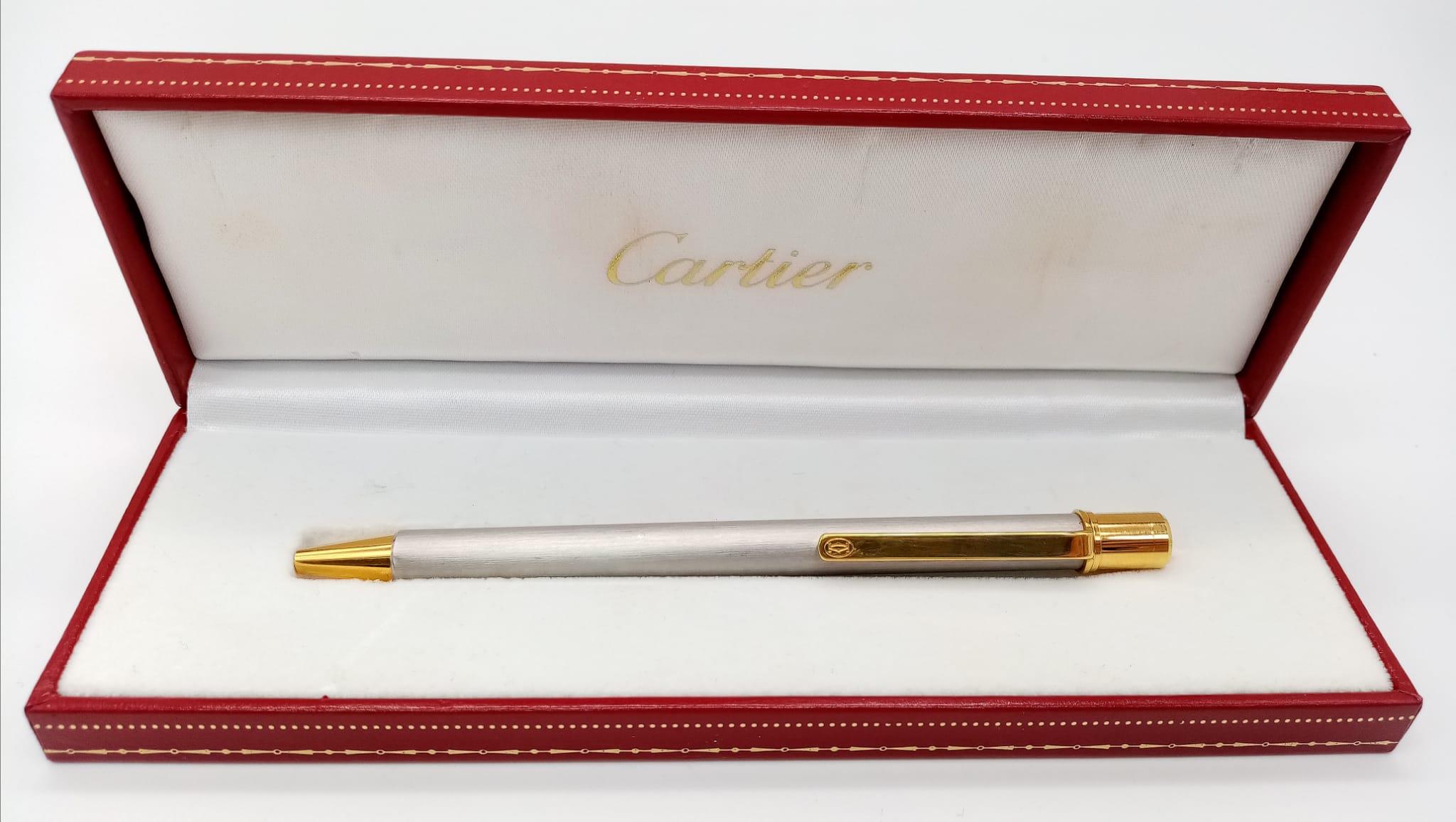 A Cartier Brushed White Metal and Gilded Ballpoint Pen. 13cm. Comes in its original Cartier case.