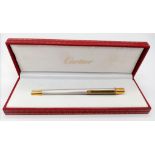 A Cartier Brushed White Metal and Gilded Ballpoint Pen. 13cm. Comes in its original Cartier case.