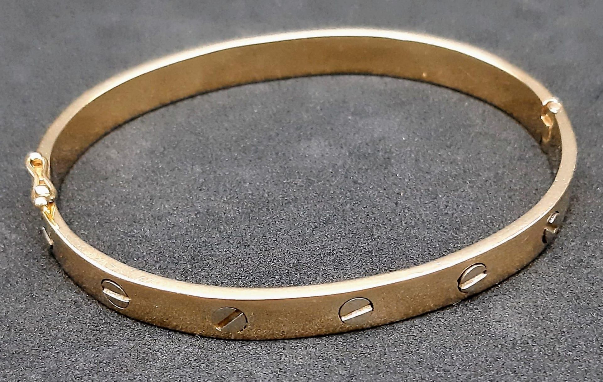 A 14K Yellow Gold Cartier-Style Bangle. Clip-open design for easy access. 62mm inner diameter. 22.
