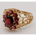 1960’s oval cluster garnet ring surrounded by a halo of bright red garnets in a stylish bark design.