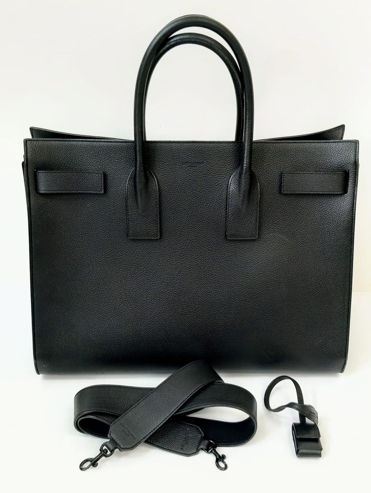 A Classy YSL Black Leather Sac de Jour Tote Bag. Textured calf leather exterior with twin handles.
