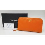A Prada Burnt Orange Leather Wallet/Clutch. Gilded touches. Spacious interior.Textile and leather